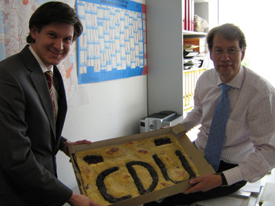 Die CDU-Bundestagsabgeordneten Dr. Ole Schröder (links) und Gero Storjohann präsentieren den riesigen CDU-Kuchen von Bäckermeister Karl Maria Kwoll aus Ellerau im Berliner Abgeordnetenbüro von Gero Storjohann